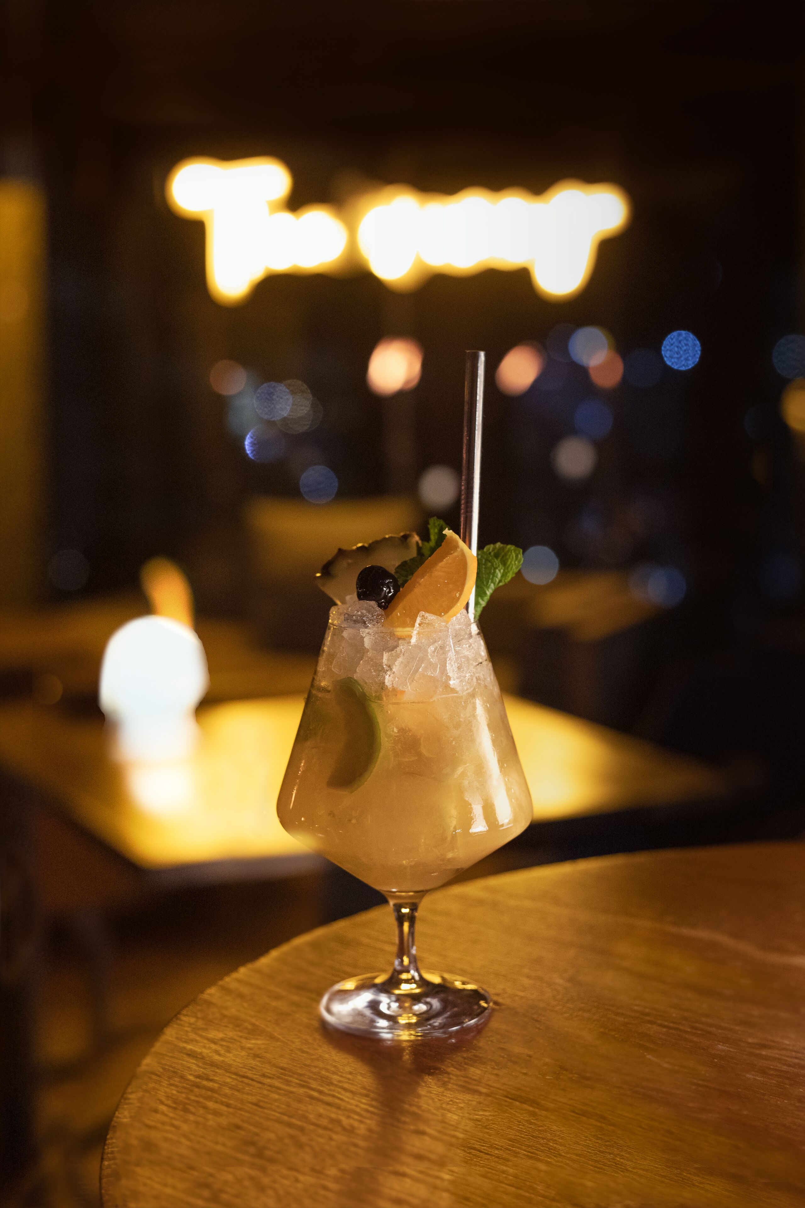 Et cocktailglas med is og pynt på et træbord.
