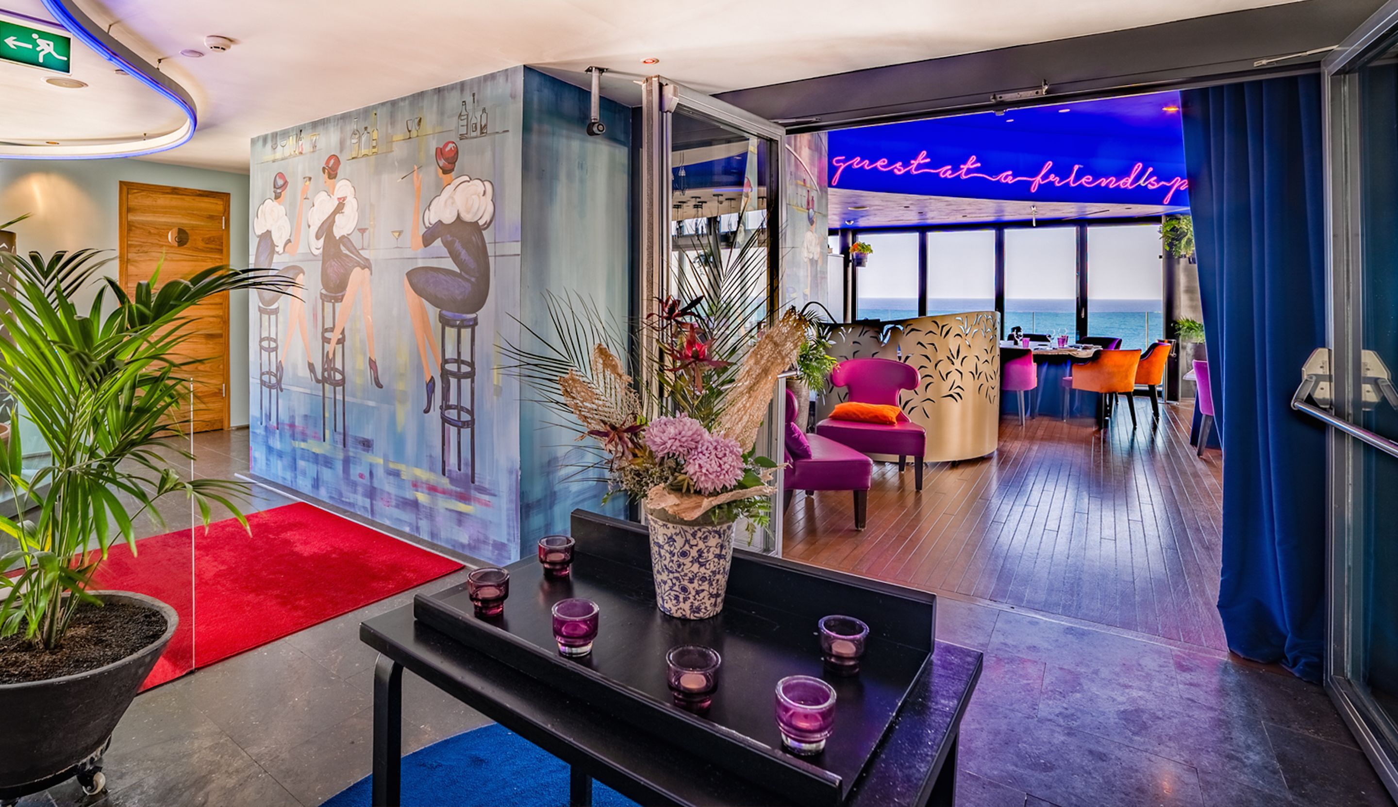 Un interior moderno con un mural vibrante, una zona de bar y vistas al mar.