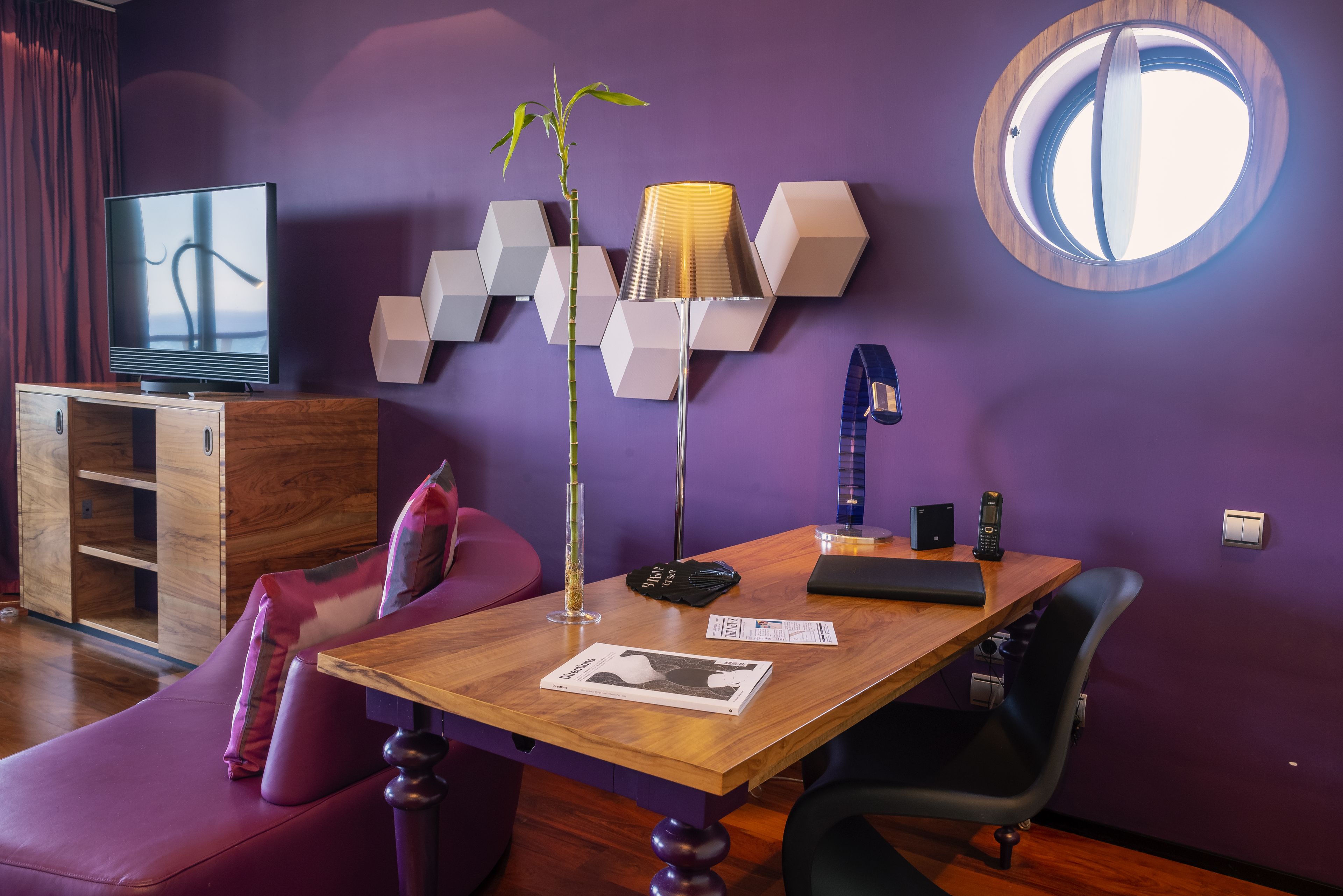 A modern living room with a wooden table, purple sofa, and a television.