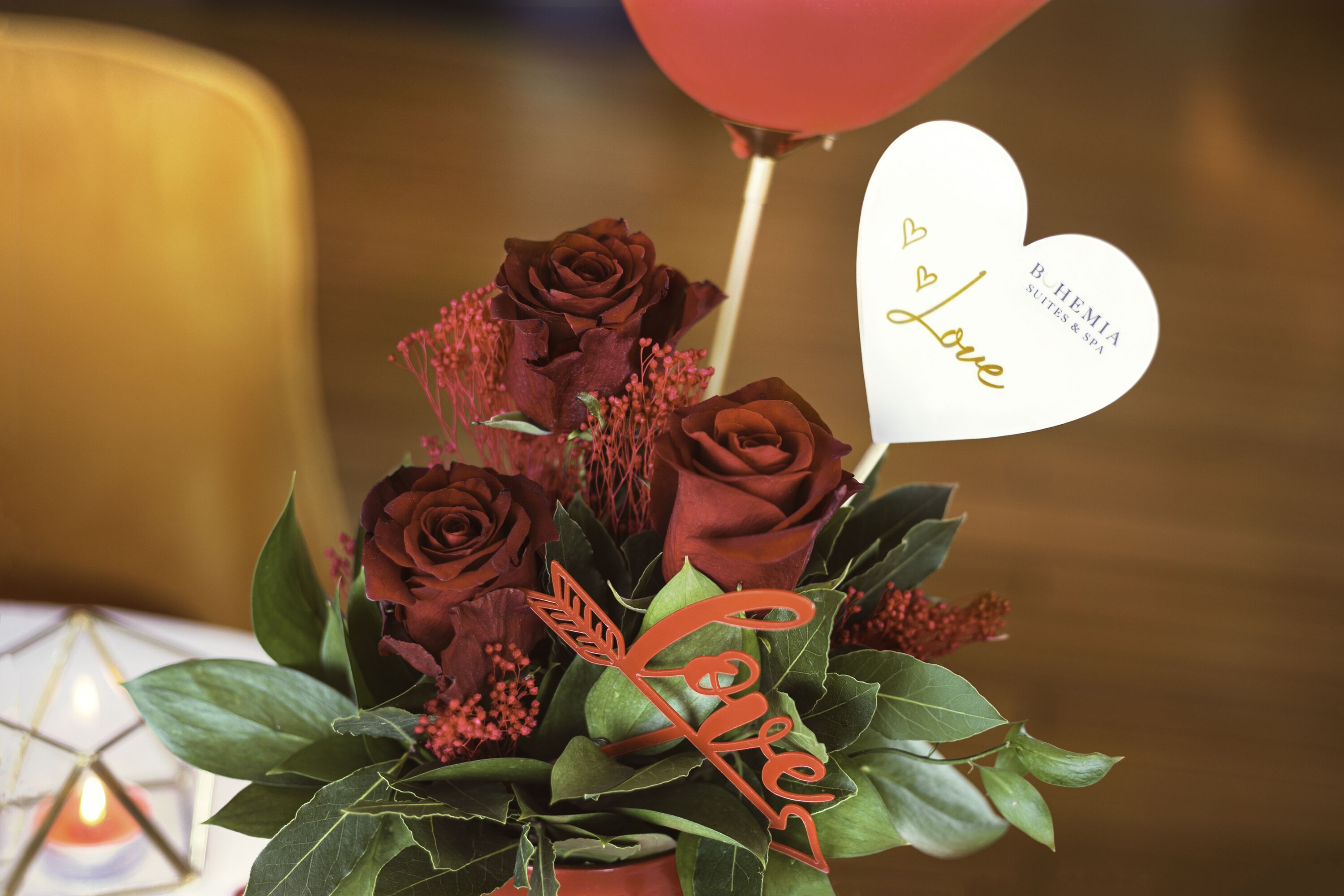 Un bouquet de roses agrémenté d’un petit panneau en forme de cœur sur lequel on peut lire « Amour » et « B. HEMIA Suites & Spa ».