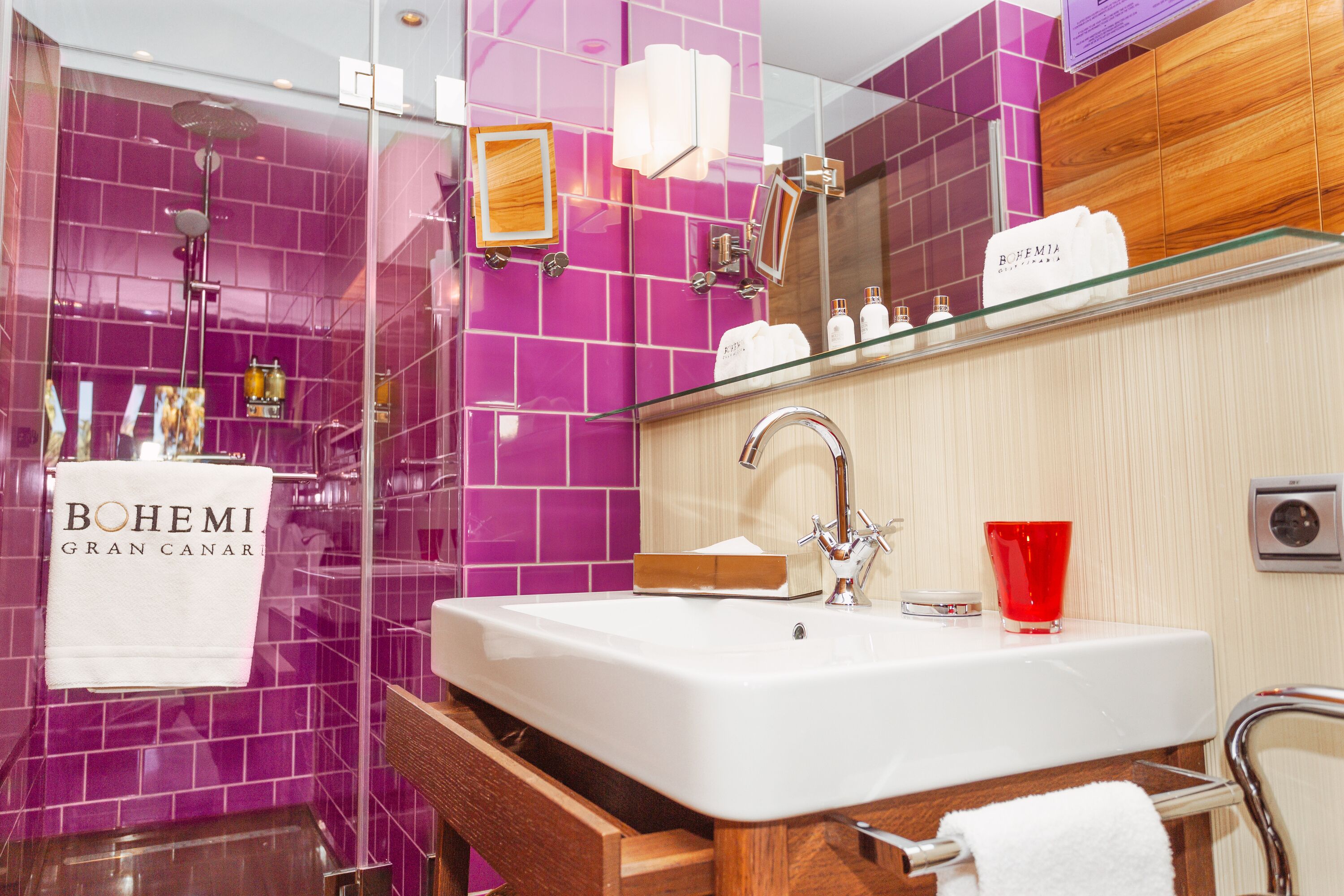 Un baño con un lavamanos grande de color blanco, cabina de ducha de vidrio y un espejo con marco de madera.