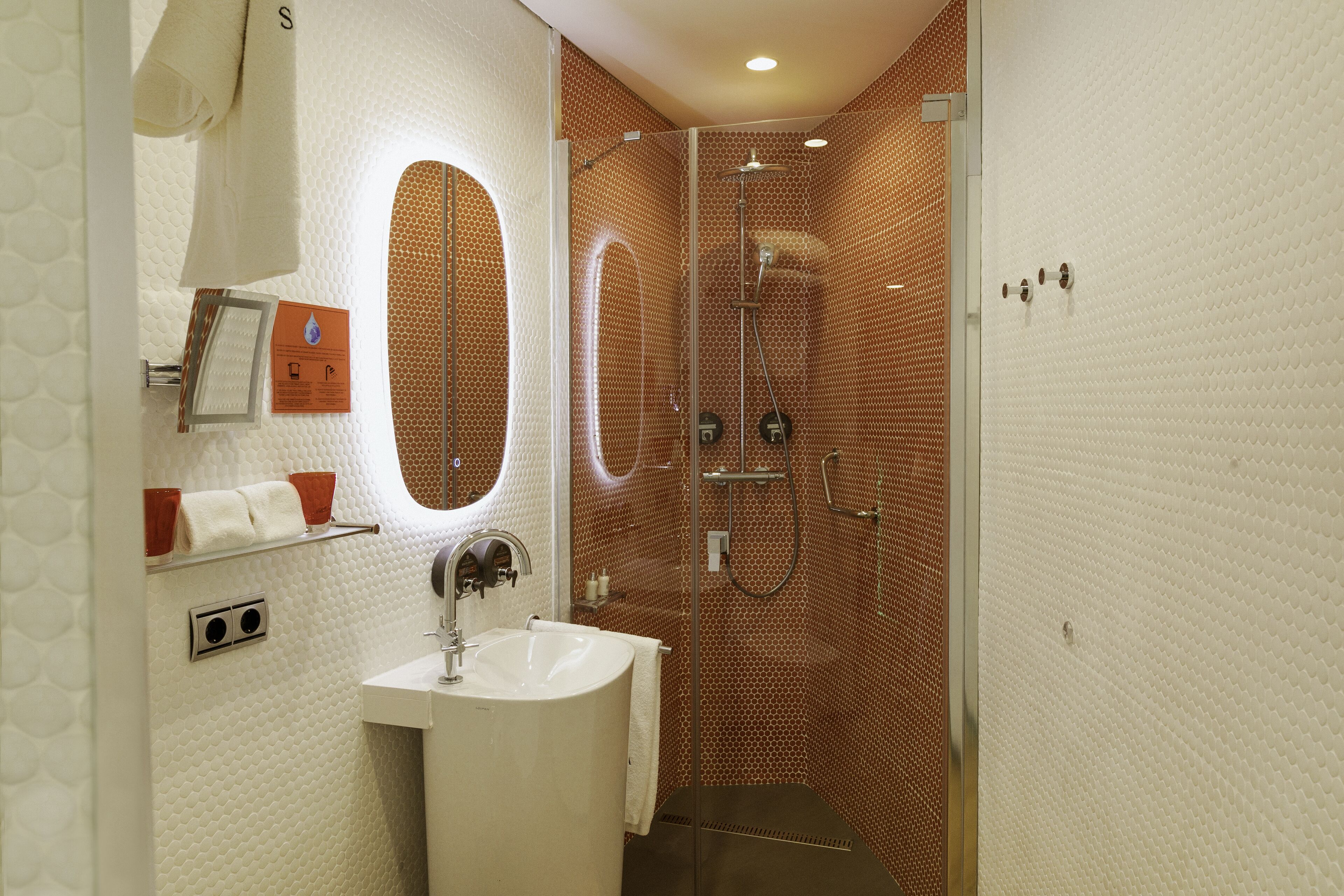 A bathroom with a sink, mirror, towel rack, and shower.