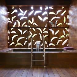 Bathroom features a large, illuminated wall with a leaf-like pattern and a metal ladder leading to a bench with a sink.