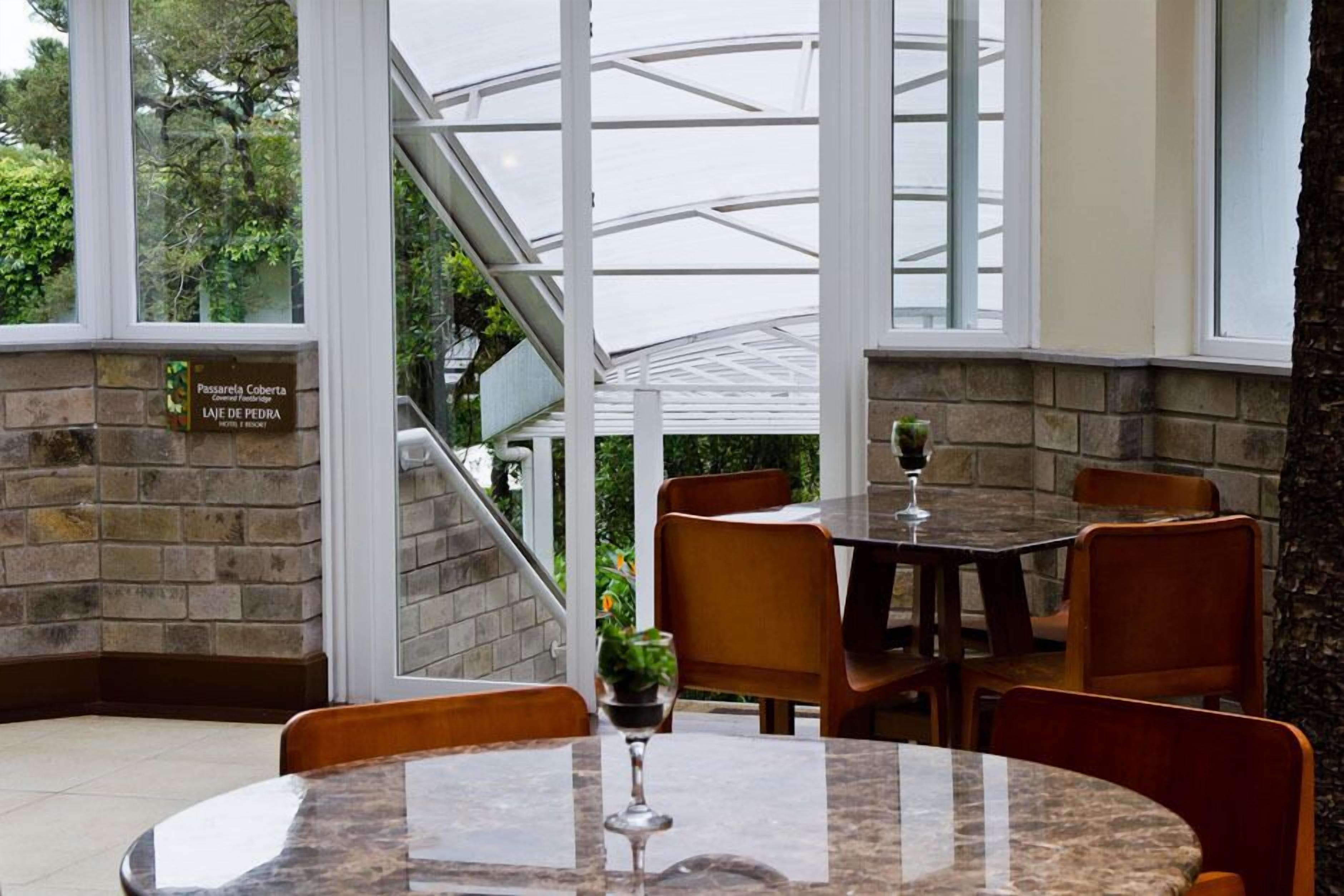 A restaurant with a glass enclosure, stone walls, and wooden furniture.