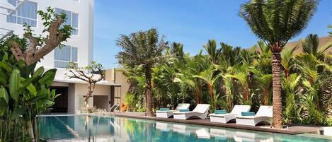 Een buitenzwembad, parasols bij het zwembad en ligstoelen