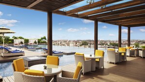 Un espace piscine aménagé sur le toit, avec des chaises longues, un jacuzzi et une vue sur le paysage urbain.