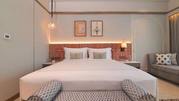 A hotel room with a large bed, two bedside tables, a sofa, and a patterned rug.