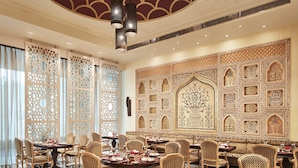 Un espace de restauration luxueux, agrémenté de décorations murales raffinées, d’un plafond haut et de meubles élégants.