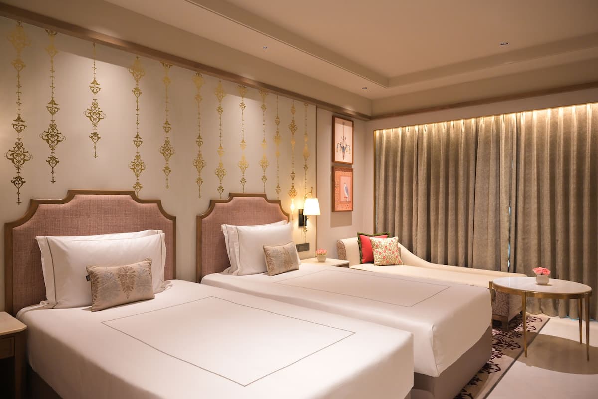 Ett hotellrum med två sängar, en sittgrupp och utsikt över staden.