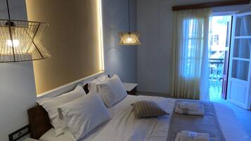 A hotel room with a neatly made bed, two bedside tables, a hanging lamp, and a view of the outside.