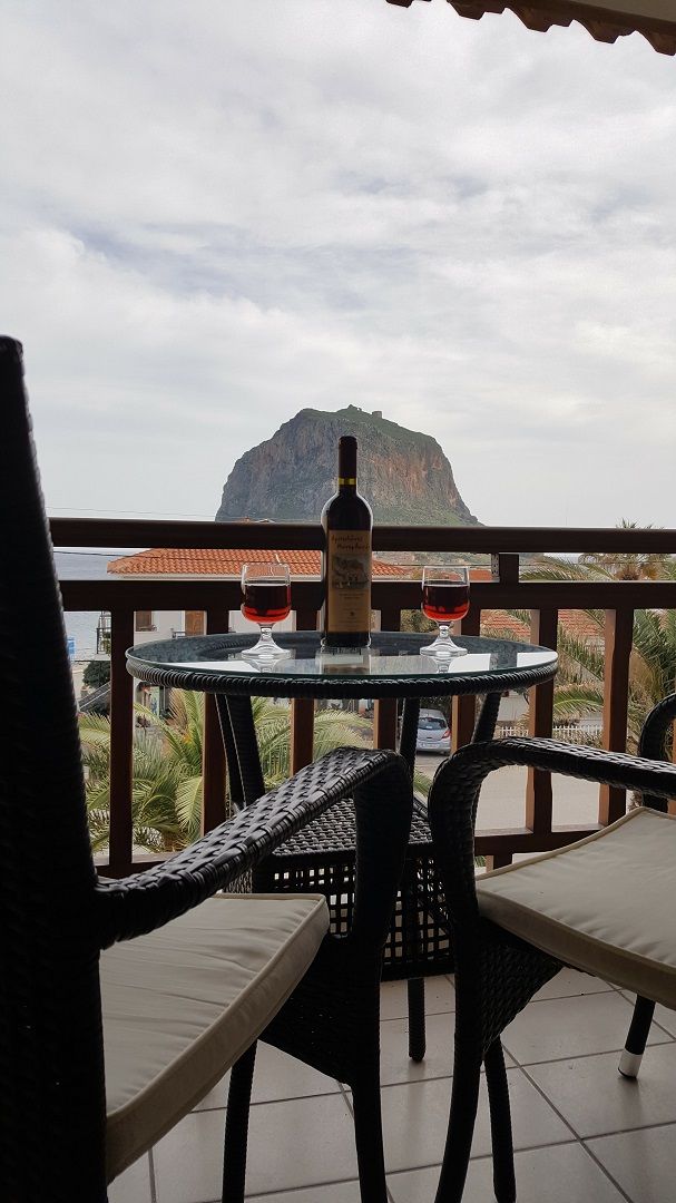 Un balcón con una mesa y sillas, una botella de vino y dos copas sobre la mesa.