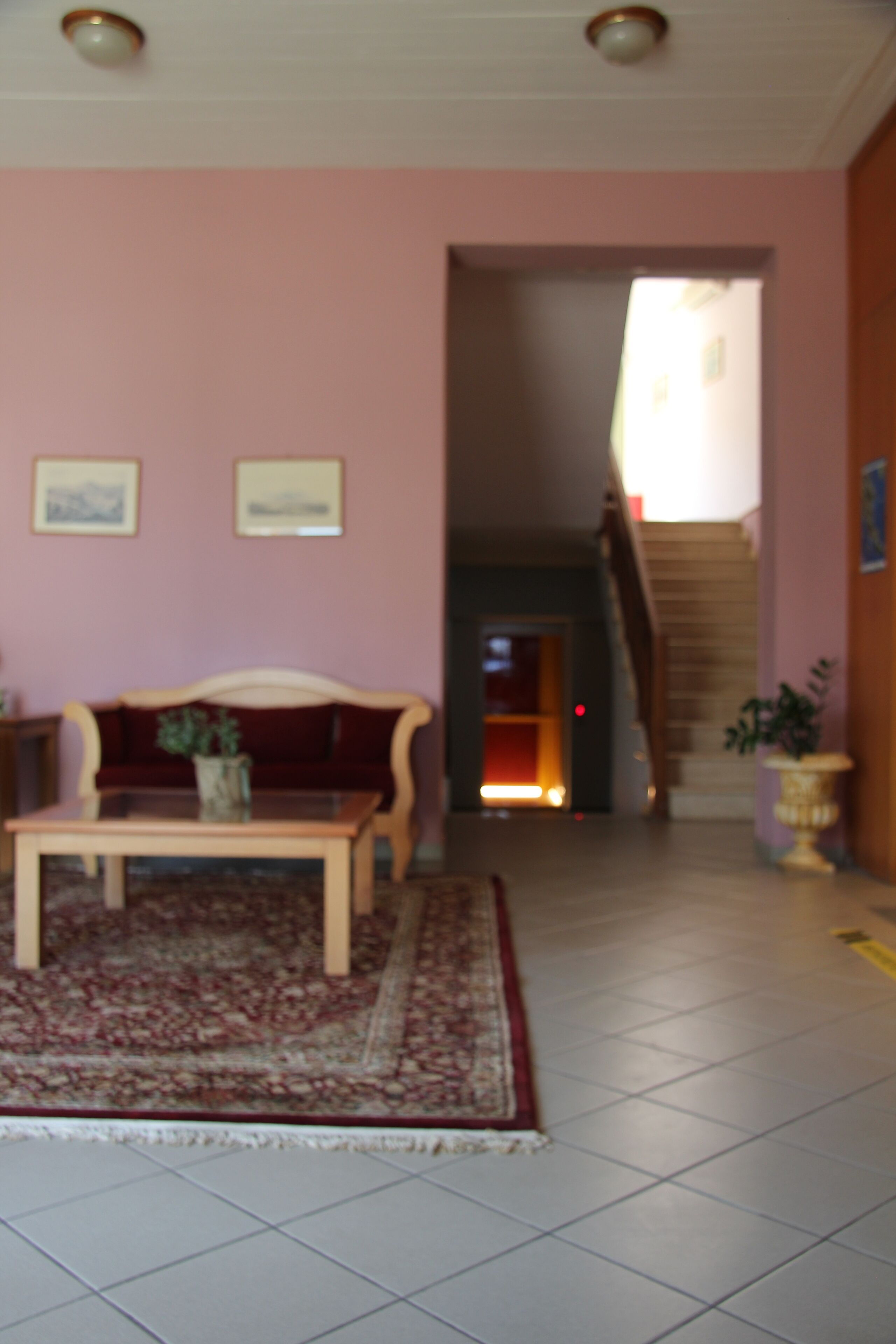 Ein Wohnzimmer mit Sofa, Couchtisch und Teppich. Eine Treppe führt zu einer weiteren Ebene.