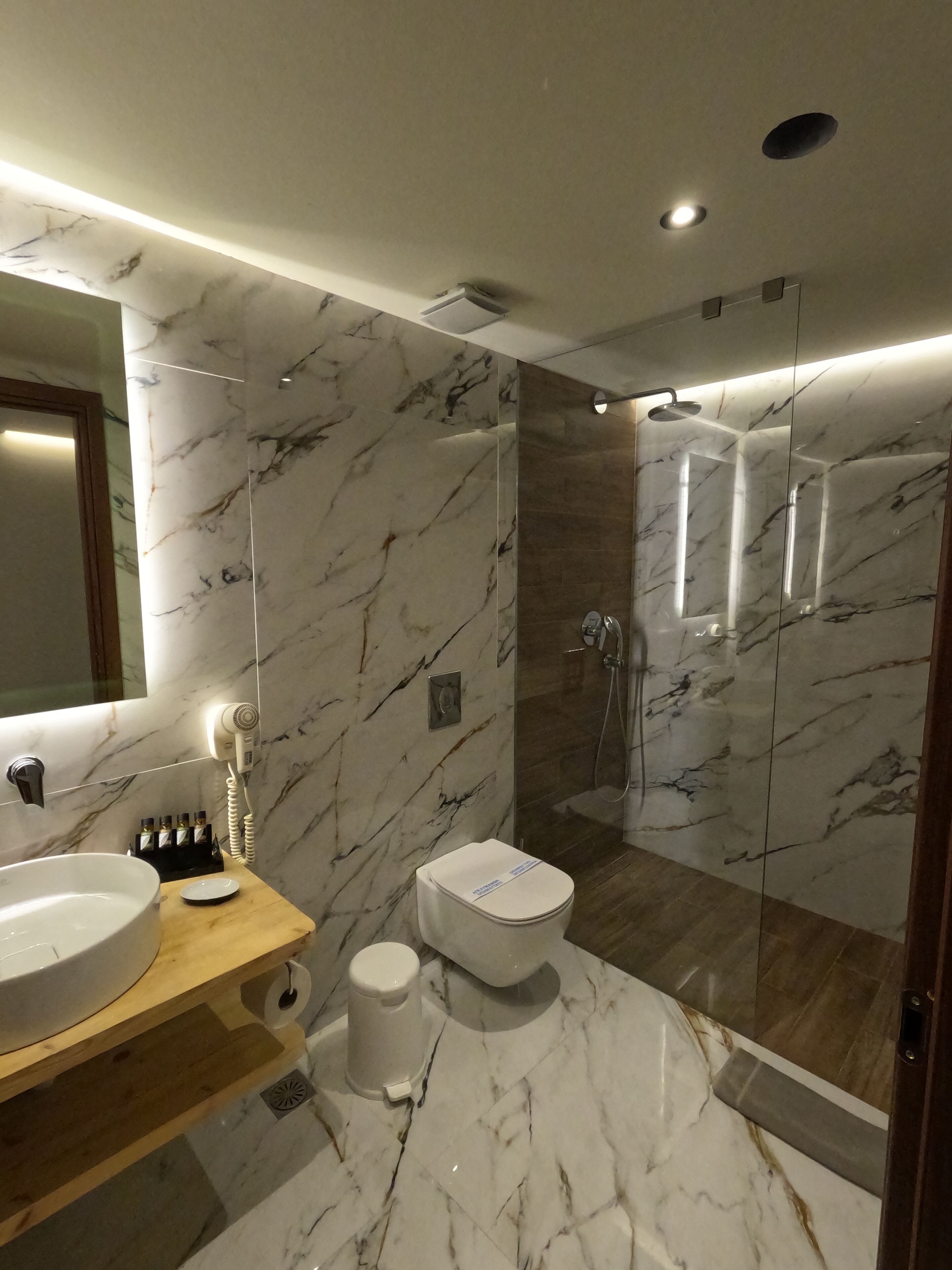 Une salle de bain moderne avec un meuble-lavabo en marbre, une douche à parois de verre et des toilettes.