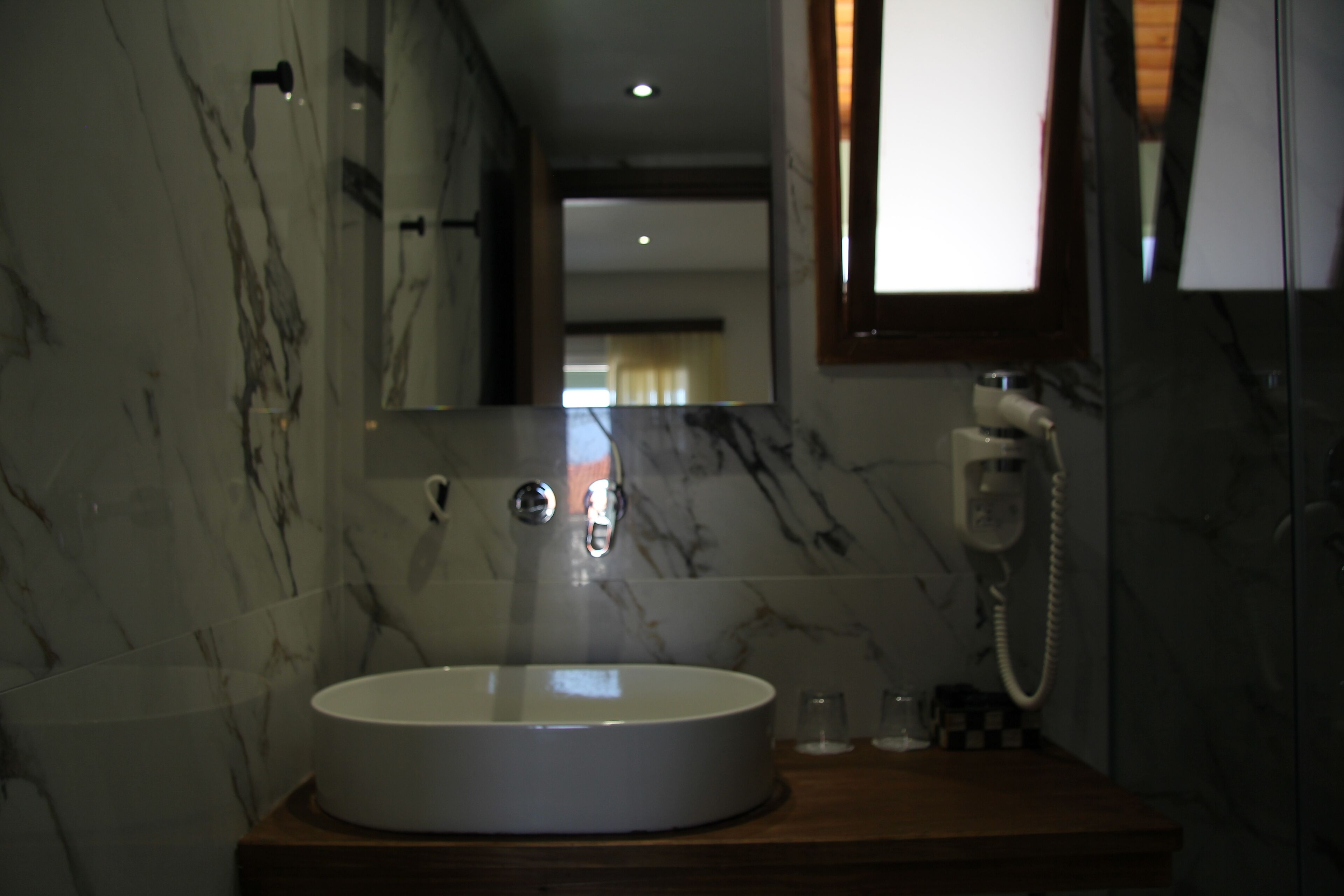 Une salle de bain avec un mur en marbre, un lavabo rond, un miroir et un téléphone.