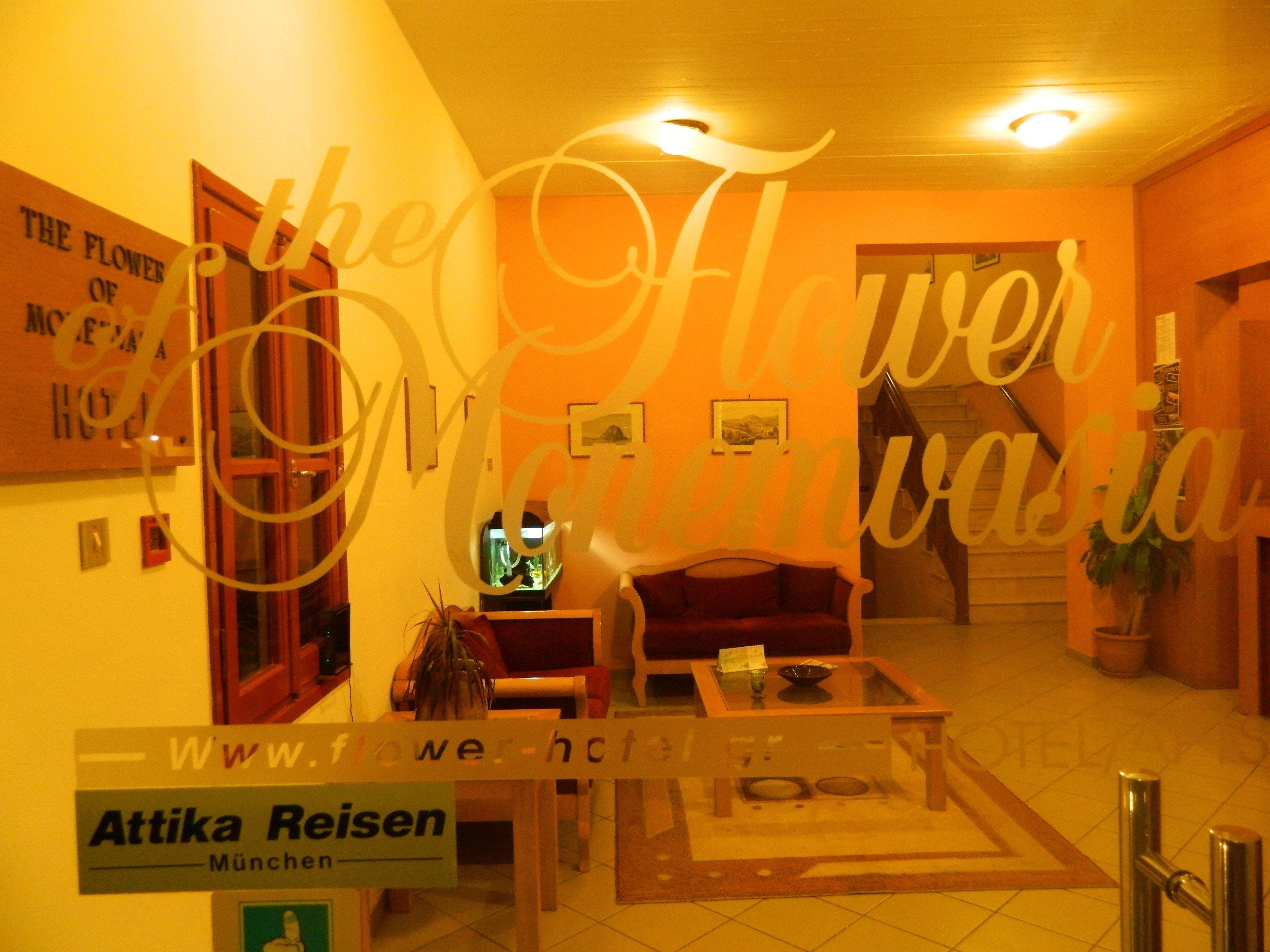A hotel lobby with a sofa, a coffee table, and a television. There is a sign for Attika Reisen in Munich.