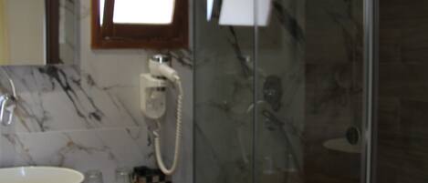 A modern bathroom with a marble sink, a glass shower enclosure, and a visible telephone.