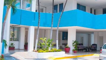 Un edificio de varios pisos con paredes azules y blancas, palmeras y plantas en macetas.