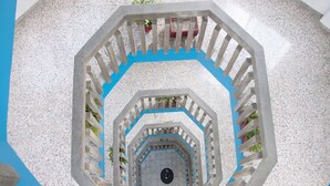 A spiral staircase with a geometric design, surrounded by a textured wall and a blue floor. - Dorados Acapulco (Acapulco)