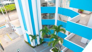 A multi-level building with blue and white exterior walls, a central atrium with a spiral staircase, and palm trees. - Dorados Acapulco (Acapulco)