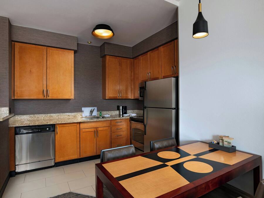 A modern kitchen with wooden cabinets, stainless steel appliances, and a dining table with a geometric design.
