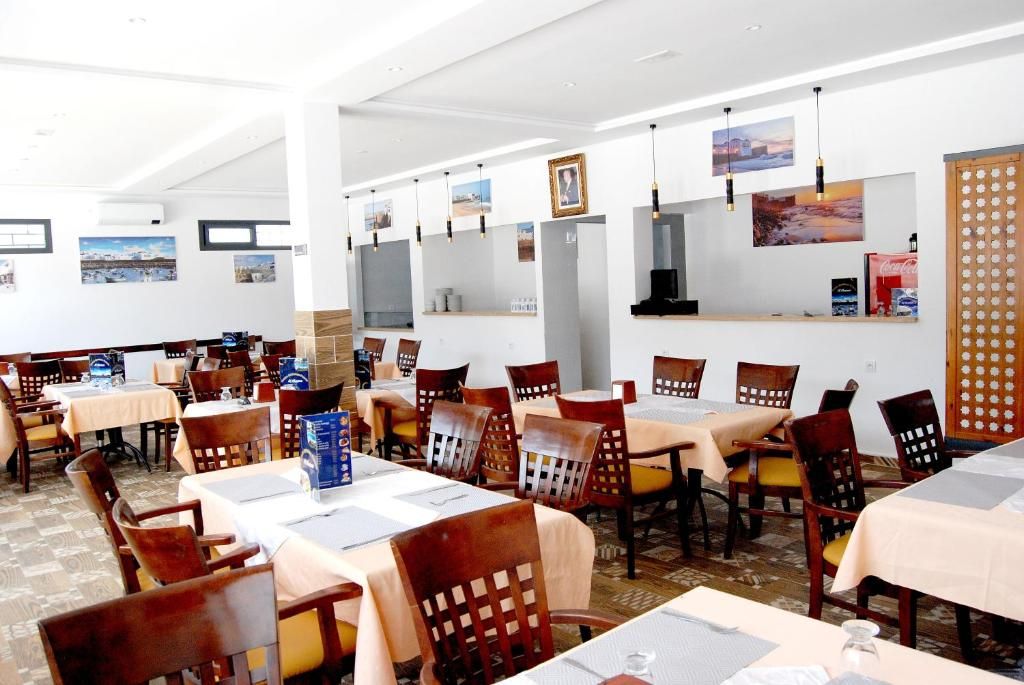 Un restaurante con varias mesas y sillas, cuadros en las paredes y un separador de madera.