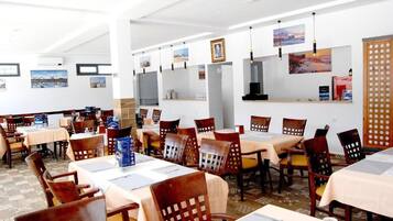 Un restaurante con varias mesas y sillas, cuadros en las paredes y un separador de madera.