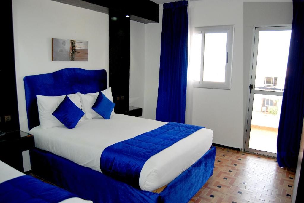 Een hotelkamer met een bed, nachtkastje, raam en deur.