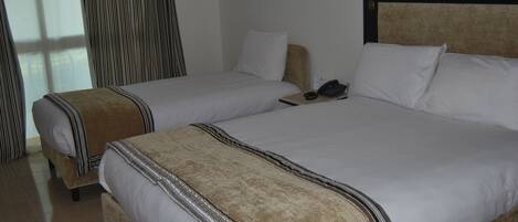A hotel room with two beds, a telephone, and a decorative wall piece.