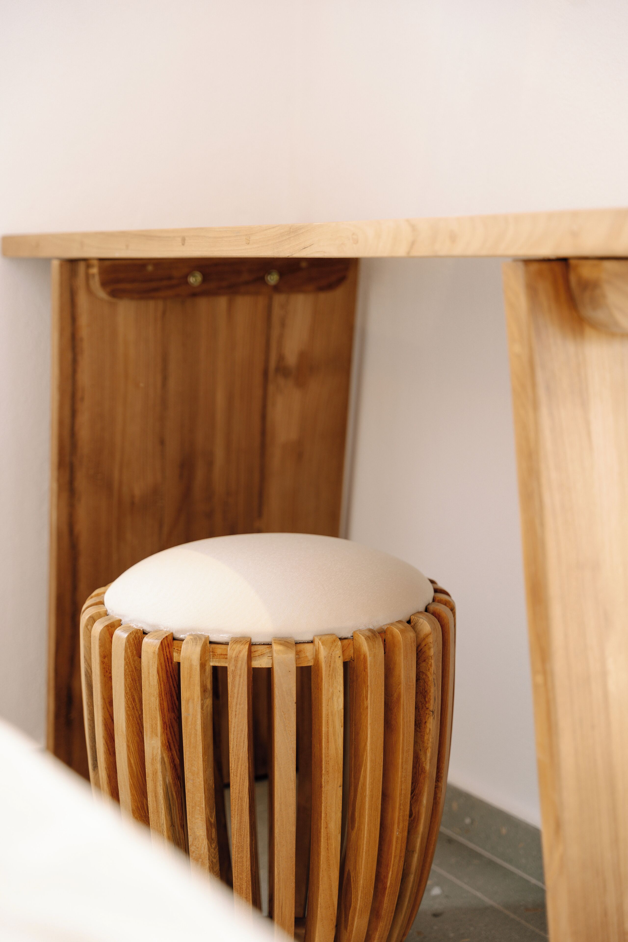 A wooden stool with a cushioned seat and a wooden table with a simple design.