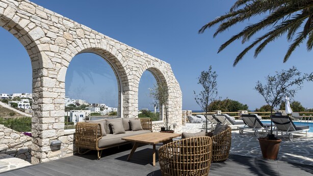 A rooftop terrace with stone arches, wicker furniture, and a pool area.