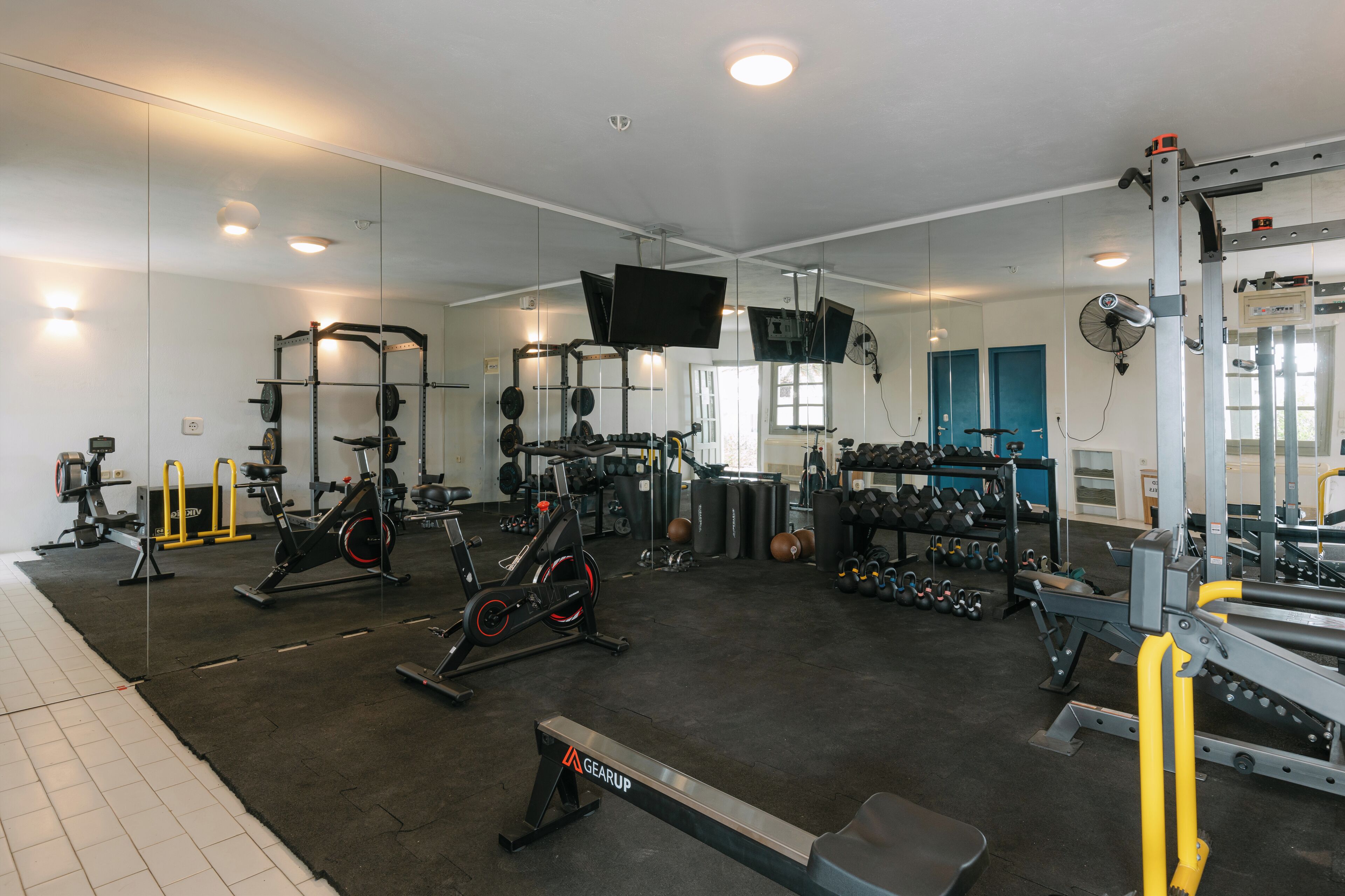 A gym with various exercise equipment, including treadmills, weight machines, and free weights.
