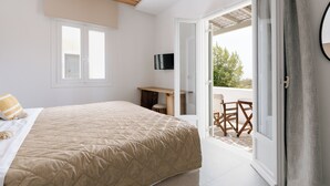 A bedroom with a bed, a TV mounted on the wall, and a balcony with outdoor furniture.