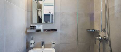 A modern bathroom with a sink, mirror, and shower.