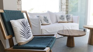 A modern lounge area with a wooden chair and sofa set, featuring a round wooden table.