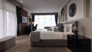 A modern bedroom with a large bed, bedside tables, a desk, and a large window with curtains. - Villa Monticello (Accra)