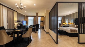 A hotel room with a dining area, a TV, a bed, and a separate living area. - Villa Monticello (Accra)