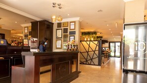 A reception area with a dark wooden desk, framed awards, and a glass partition. - Villa Monticello (Accra)