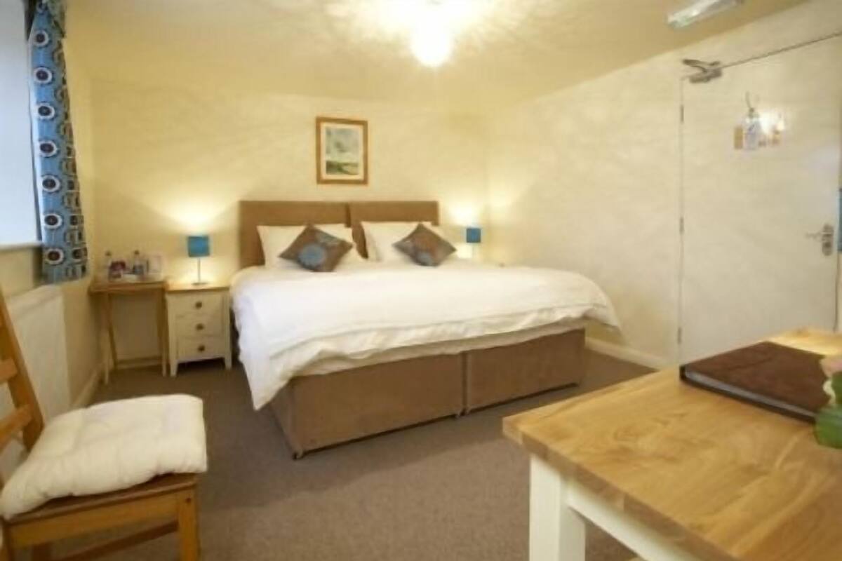 A bedroom with a bed, bedside tables, a desk, and a wardrobe.