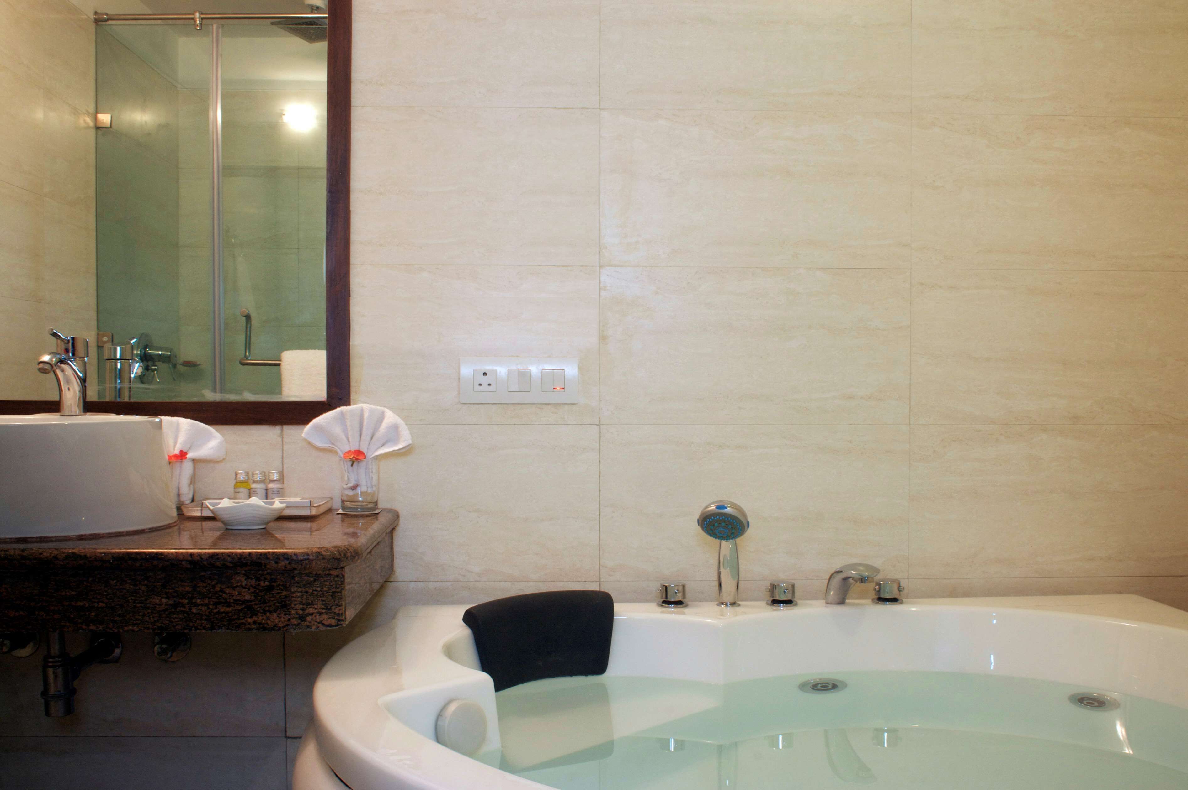 Un baño con una bañera grande, un lavamanos y un espejo.