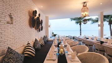 Enjoy meals in this beautifully set dining area with a long table, wicker chairs, and a decorative lantern.