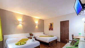 A hotel room with two beds, a wooden bench, a small table, and a TV mounted on the wall. - Hotel Hacienda Vallarta Playa Las Glorias (Puerto Vallarta)