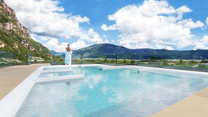 A swimming pool with a view of mountains and a person standing by the pool. - Art & Design Hotel Napura (Terlano)