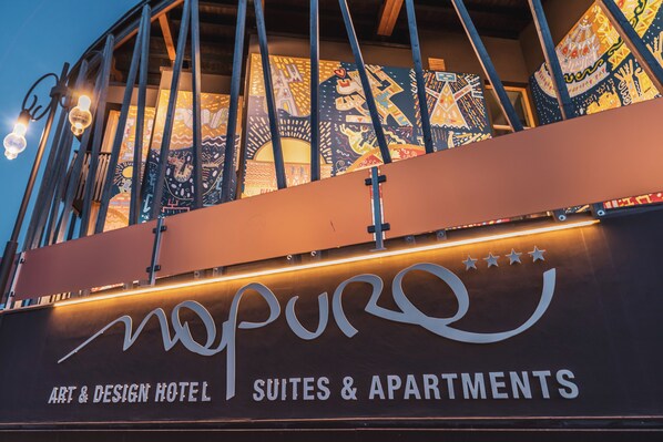 The exterior of the Nopuro Art & Design Hotel, featuring a modern architectural design with a prominent signboard displaying the hotel's name and services. - Art & Design Hotel Napura (Terlano)