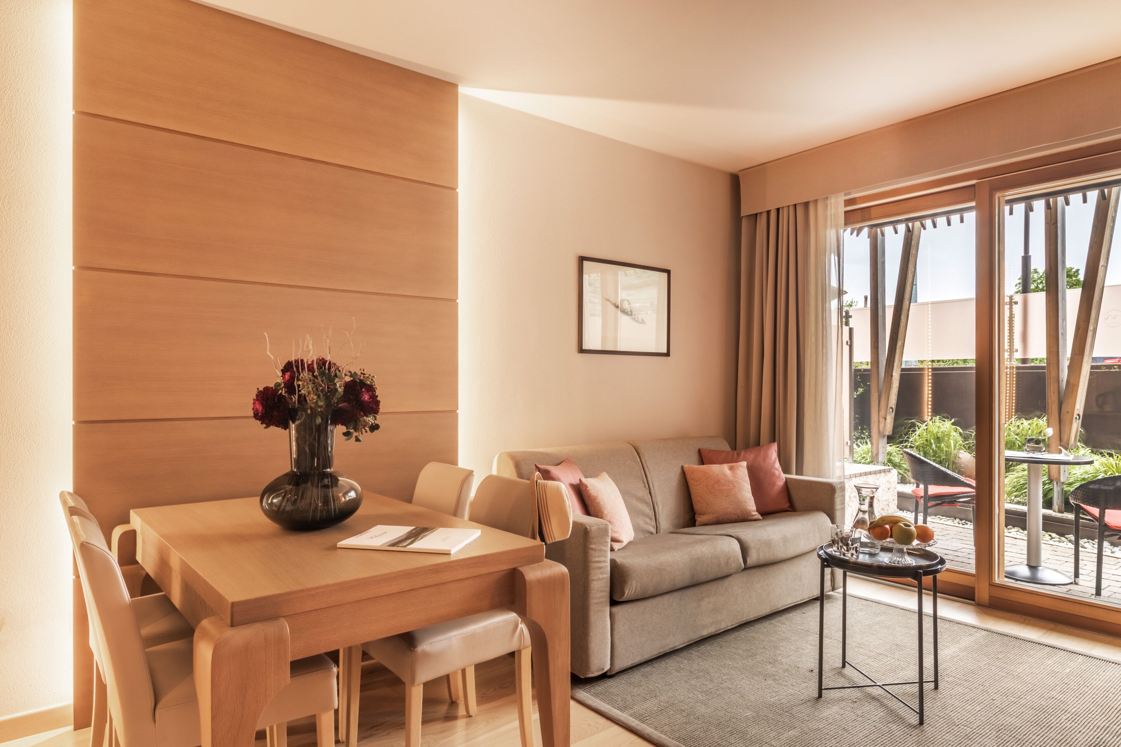 Un salón moderno con una mesa de comedor de madera, un sofá y una mesita auxiliar con frutas.
