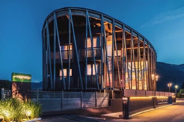 A modern building with a curved glass facade, a prominent entrance with a sign, and a well-lit exterior.