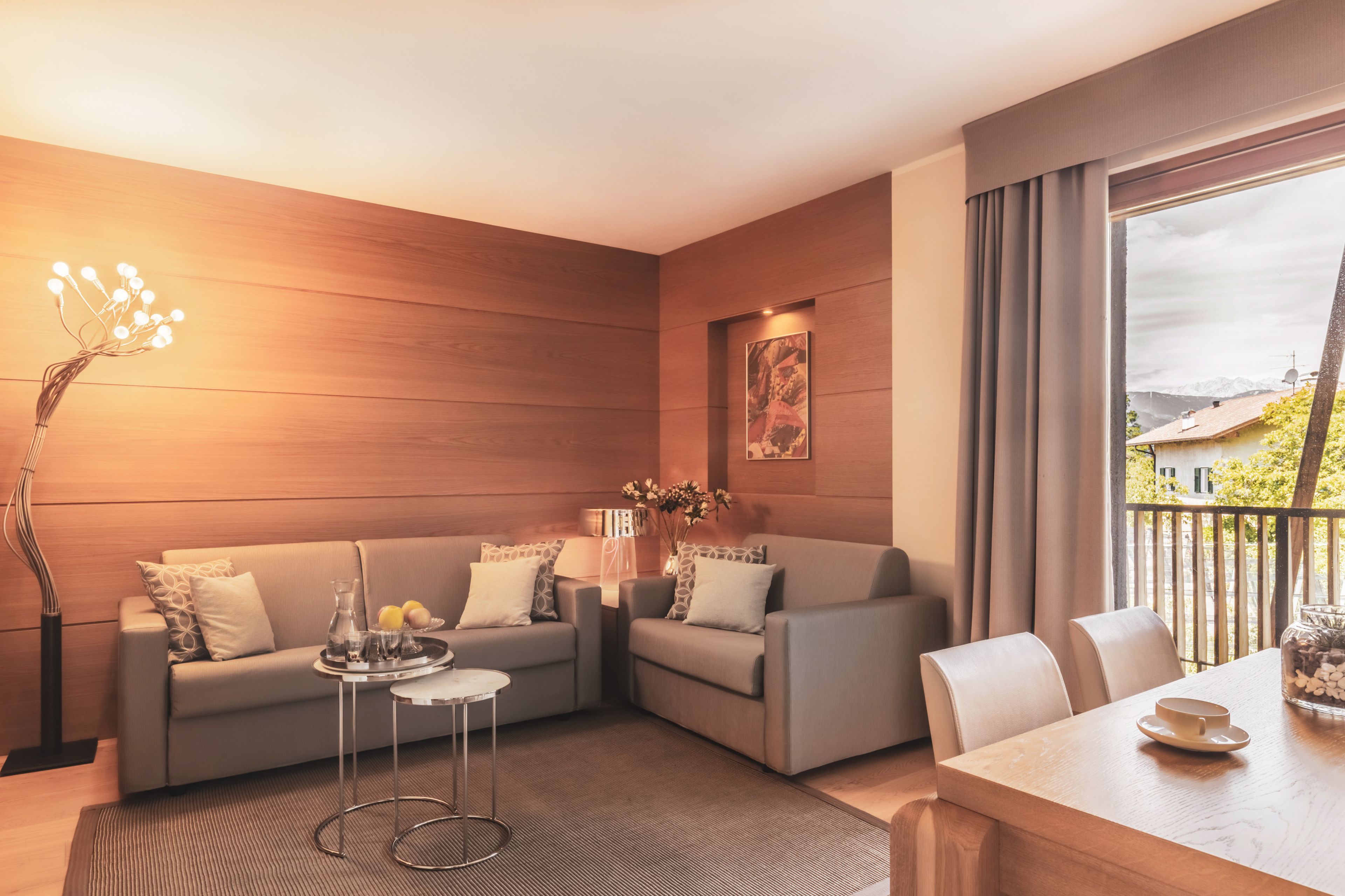 Una sala moderna con sofá, mesa de centro y mesa de comedor. Hay un florero con flores sobre la mesa de centro y un cuadro en la pared.