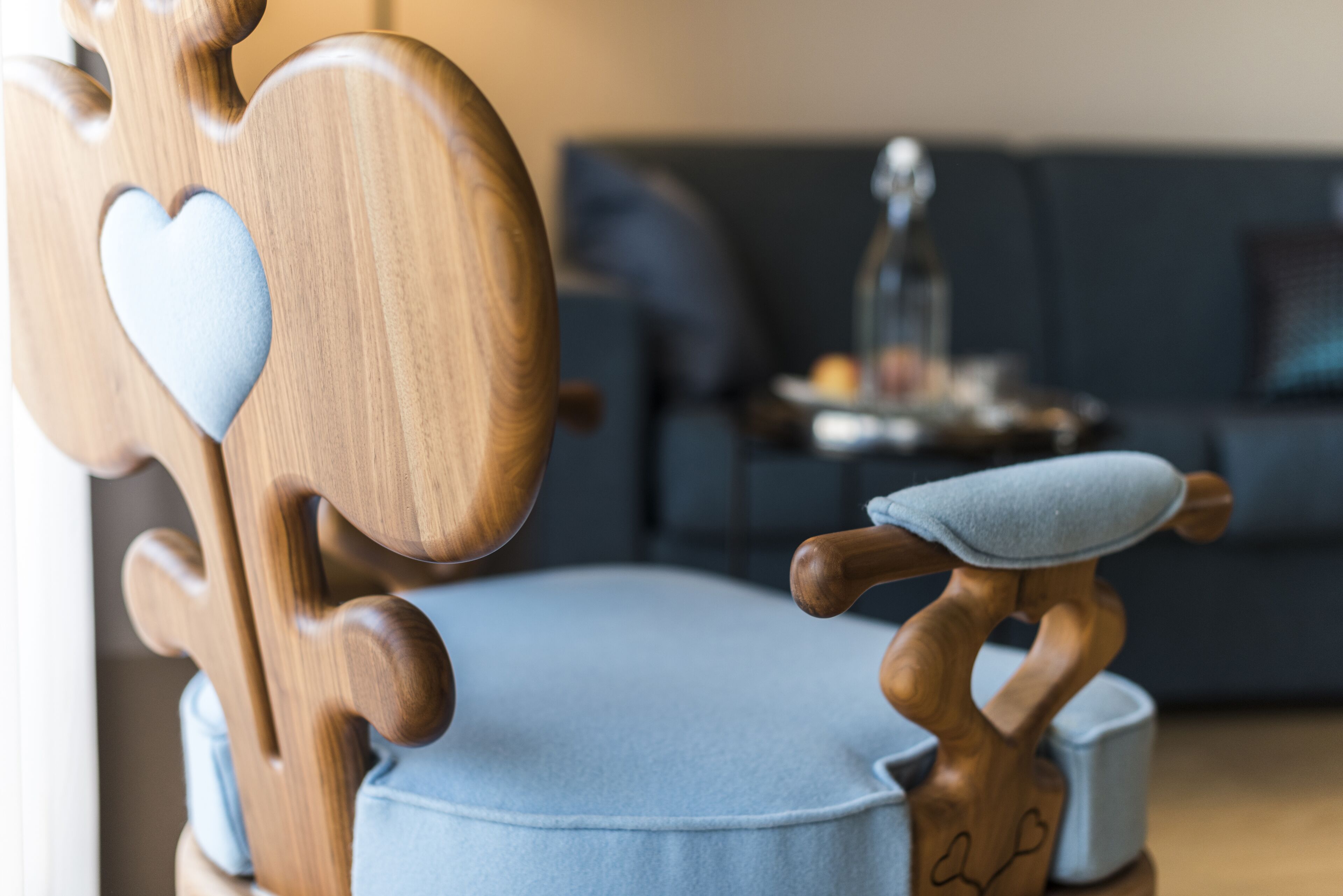 A wooden chair with a heart-shaped cutout and a cushion.