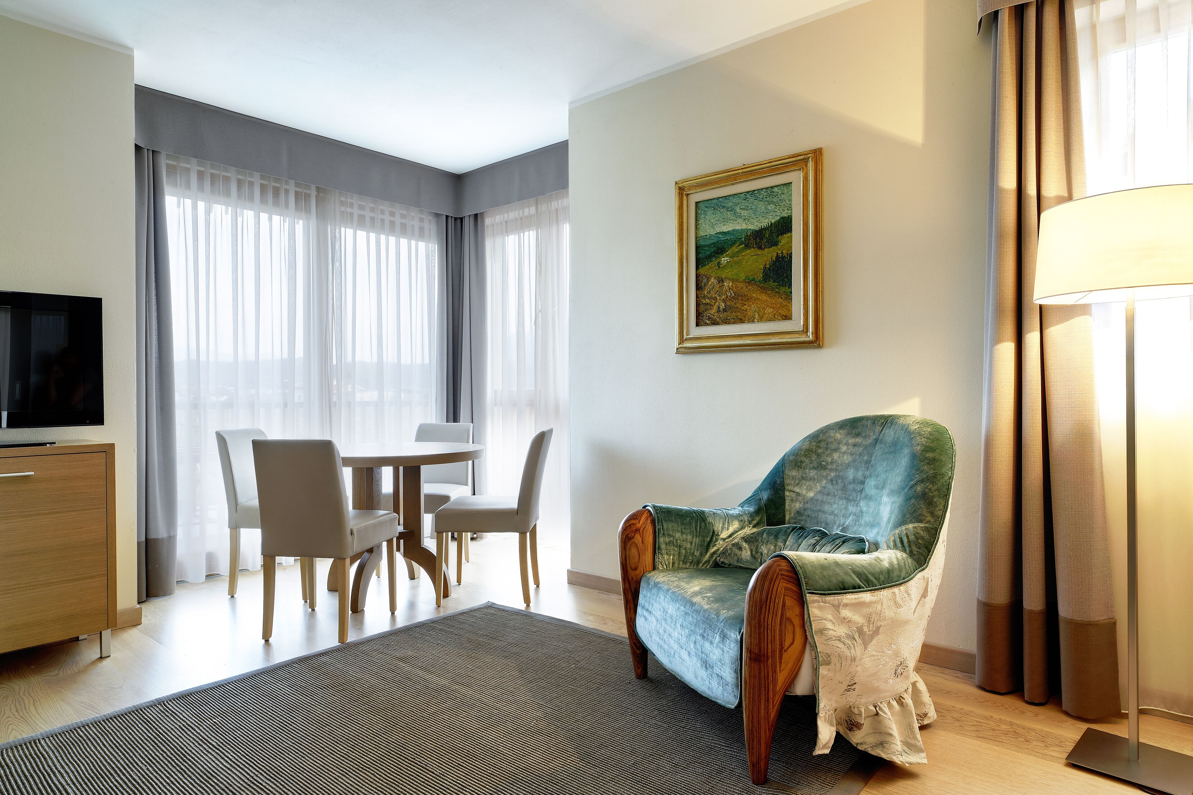 Een moderne woonkamer met een bank, een eettafel met stoelen, een televisie en een schilderij aan de muur.