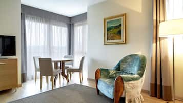 Een moderne woonkamer met een bank, een eettafel met stoelen, een televisie en een schilderij aan de muur.