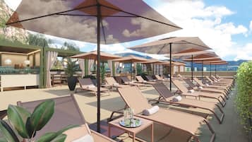 Un espace de détente sur le toit, avec des chaises longues et des parasols, un bar et une vue sur les montagnes.